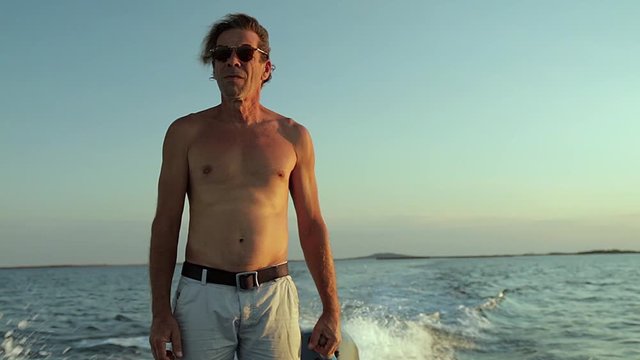 Un homme navigue debout sur une barque. On voit des parcs &agrave; hu&icirc;tres &agrave; l'horizon.