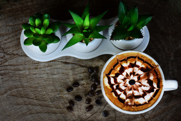 White ceramic coffee cup with cappuccino and latte art placed on an old wooden floor.