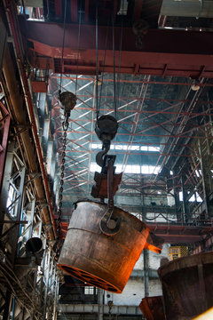 Metallurgy plant interior. Melting of metal. Metallurgy bucket with liquid hot metal. Orange light of furnace.