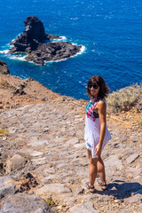 A young tourist walking on the cliff path on the descent to the black sand beach of Bujaren, north of the island of La Palma, Canary Islands. Spain