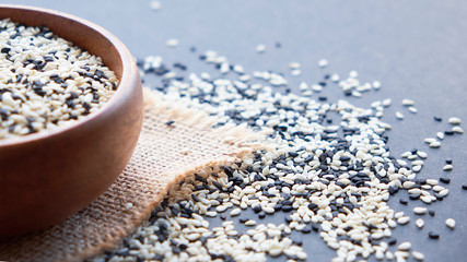 Organic natural sesame seeds wooden spoon. toasted sesame seeds. Raw, whole, unprocessed. Natural light. Selective focus. Close up on a black background. Top view, flat lay. copy space for text.
