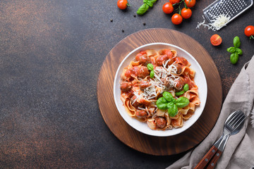 Homemade pasta fettuccine with meatballs, parmesan, tomatoes, basil on brown background. View from above.