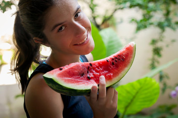  young smiling girl eats a slice of watermelon