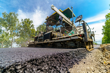 Obraz premium Selective focus on newly laid asphalt. Heavy special technic for flattering asphalt at road. Construction site.
