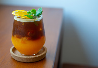 Coffee mug mixed with orange juice placed on a wooden table with writing space or design.