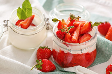 Jars of strawberry yogurt on table