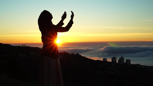 Silhouette of a Muslim woman who prays. The Religion Of Islam. Beautiful dawn, sunrise in the Holy Muslim month of Ramadan