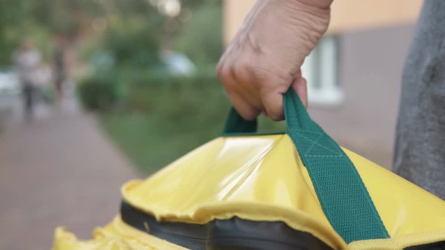 A courier with a yellow backpack delivers an online order. Stay home, self-isolation.