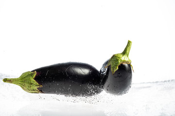 Eggplant on a white background with drops and splashes of water