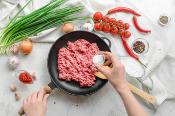 Woman preparing tasty beef casserole on light background, top view