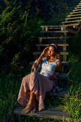 Chica joven posando en unas escaleras de madera al tardecer en la playa