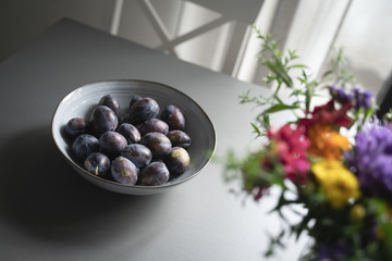 fresh plum fruits in grey bowl on table