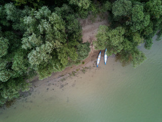 Two canoes on the shore of a river top down aerial view