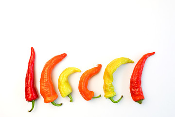 yellow, orange and red hot peppers on a white table. Concept of the harvest season, bright autumn.