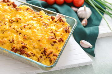 Baking dish with tasty beef casserole on color background