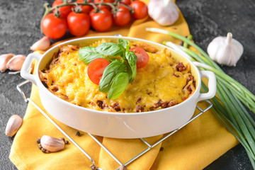 Baking dish with tasty beef casserole on dark background