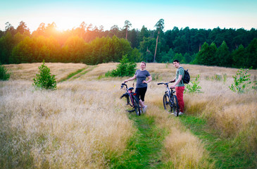 Couple on bicycles in nature. Guy with a girl with bicycles at sunset.