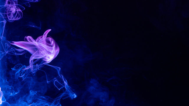 Conceptual image of multi-colored smoke isolated on dark black background, Halloween design element.