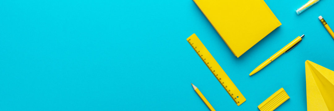 Top view photo of yellow stationery over turquoise blue background with copy space. Flat lay image of different stationary objects as back to school background.