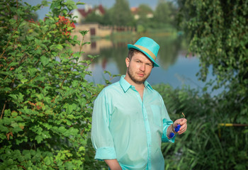 Young guy in turquoise shirt fashion outfit for men, clothes concept. Man rest at nature in fancy style