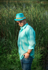 Naklejka na ściany i meble Young guy in turquoise shirt fashion outfit for men, clothes concept. Man rest at nature in fancy style