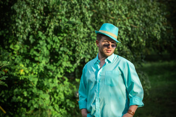 Young guy in turquoise shirt fashion outfit for men, clothes concept. Man rest at nature in fancy style
