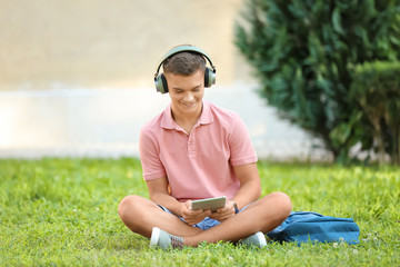 Fototapeta premium Teenage boy listening to music in park