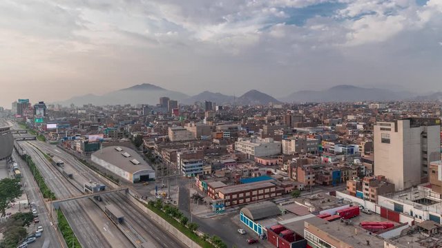Aerial panoramic view of Via Expresa highway and metropolitan bus with traffic timelapse near National Stadium of Peru. Houses and city skyline with mountains on a background. Lima, Peru