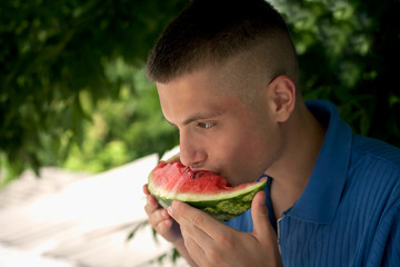young smiling guy eats a slice of watermelon