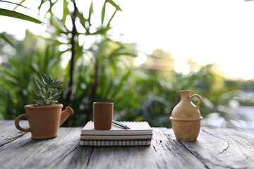 brown wooden tea cup and clay pot with succulent plant and notebook