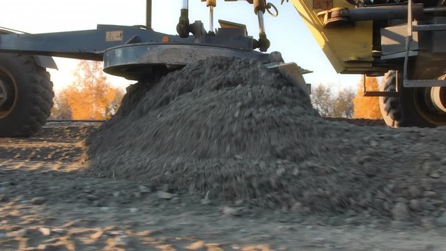 The motor grader levels bulk building materials for new construction. Road surface repair. Construction of a new road. Road construction machines. Men at work.