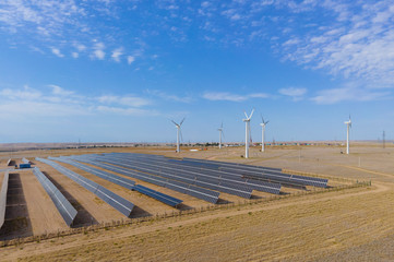 A drone photo above a new type of power plant, green energy, solar panels and wind turbines at one...