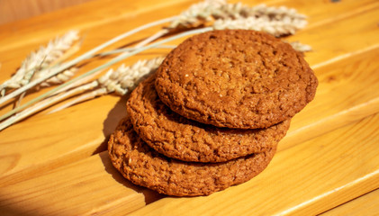 Oatmeal cookies with ears of wheat on a wooden table