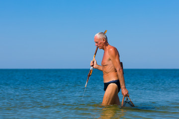 Man with a homemade spear looks out for prey in the sea.