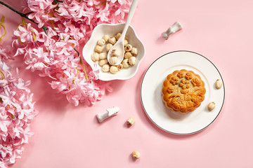 Top view Mid autumn festival moon cake, lotus seed and tea on pink background.