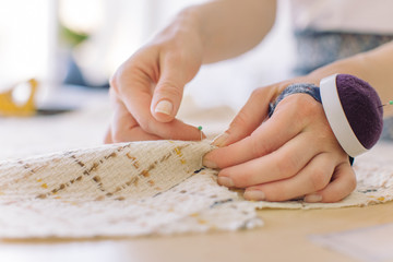 Closeup of tailor working in atelier. Sewing process. Workplace of dressmaker.