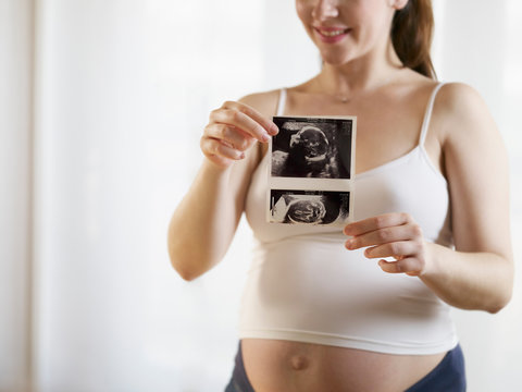 Young Pregnant Woman Showing Medical Baby Scans