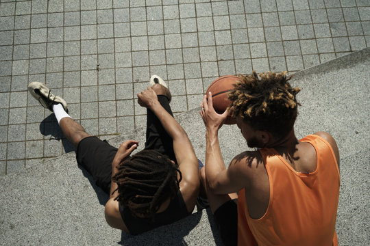Image of african american guys resting with basketball after game