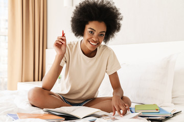 Image of cheerful african american girl smiling while doing homework