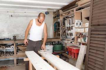 Male carpenter working on old wood in a retro vintage workshop.