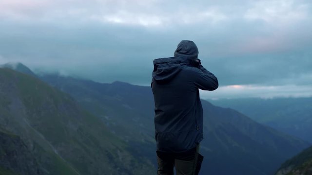Young traveler photographer takes pictures in the mountains in the evening