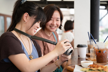 Couple of Asian woman smiling while looking at the camera at the cafe.