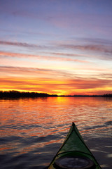 View from bow (prow) of green kayak at colorful sunset over Danube river at autumn time