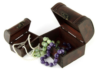 Jewelry box, pearl necklaces, semi-precious stones placed on white.
