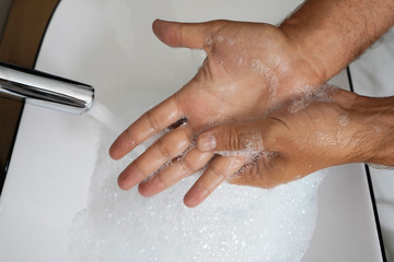 close up of man washing hands with soap in bathroom