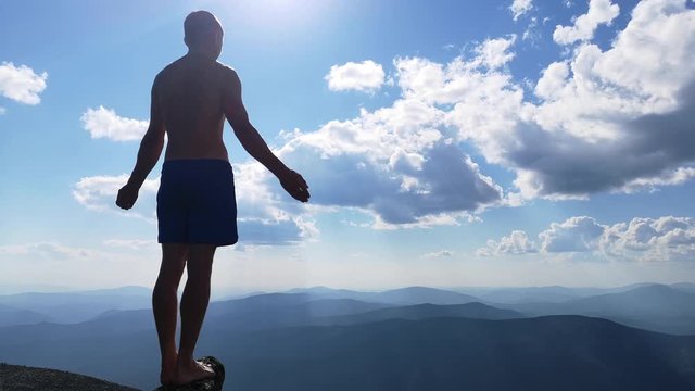 man stands on top of a mountain with open hands. at the top of the mountain, a man with his arms spread wide.