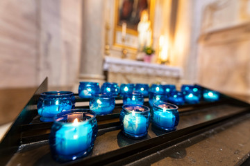Altare votivo con lumini e candele blu alla Madonna e ai Santi protettori del fedele per offerte e celebrazioni sacre o religiose