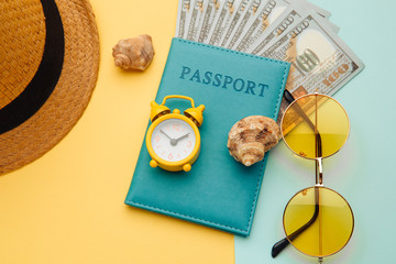 Fototapeta na wymiar Travel concept. Minimal simple flat lay with passport, sunglasses, hat and shell on yellow blue background. Tourist essentials.