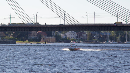 Obraz premium Riga. Daugava river. Cable-stayed bridge. Fast boat on the river.