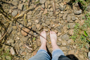 bare feet in a river with stones